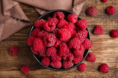 Photo of Bowl with fresh ripe raspberries on wooden table, flat lay
