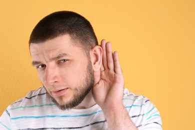 Young man with hearing problem on color background