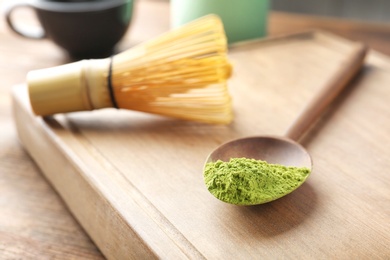 Photo of Spoon with powdered matcha tea on wooden board, closeup