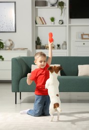 Photo of Little boy playing with his cute dog at home. Adorable pet