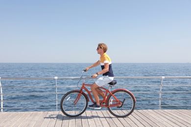 Photo of Attractive man riding bike near sea on sunny day
