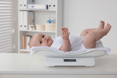 Photo of Cute little baby lying on scales in clinic