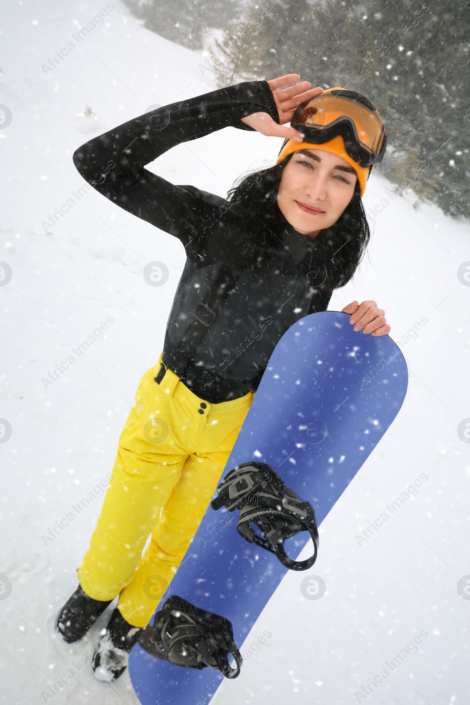 Photo of Young woman with snowboard wearing winter sport clothes outdoors