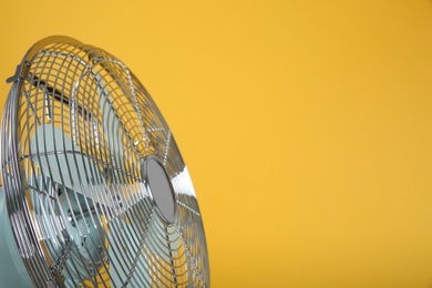 Photo of Modern electric fan on yellow background, closeup. Space for text