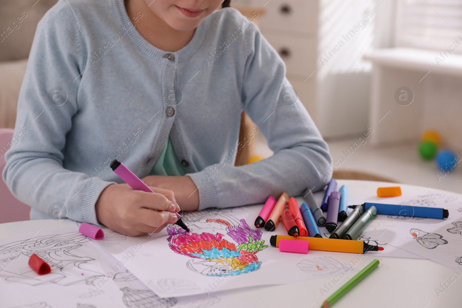 Photo of Child coloring drawing at table in room, closeup