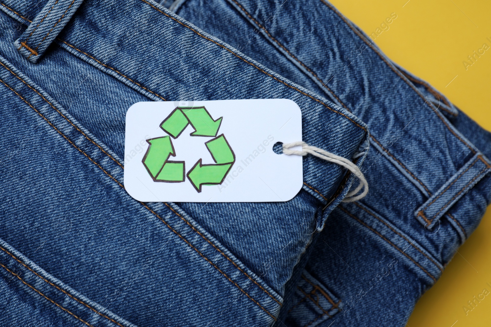 Photo of Stack of jeans with recycling label, closeup