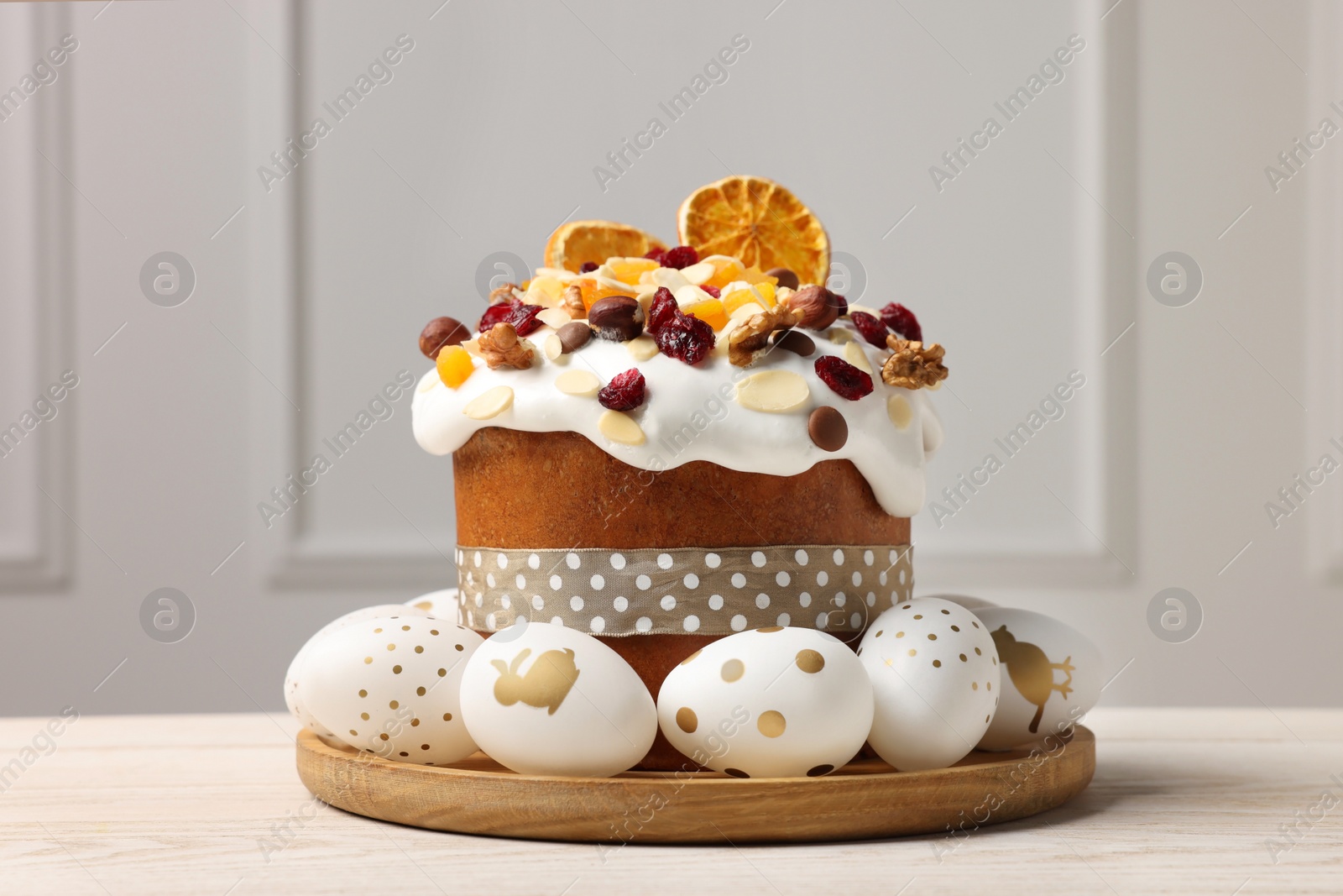 Photo of Traditional Easter cake with dried fruits and decorated eggs on white wooden table indoors