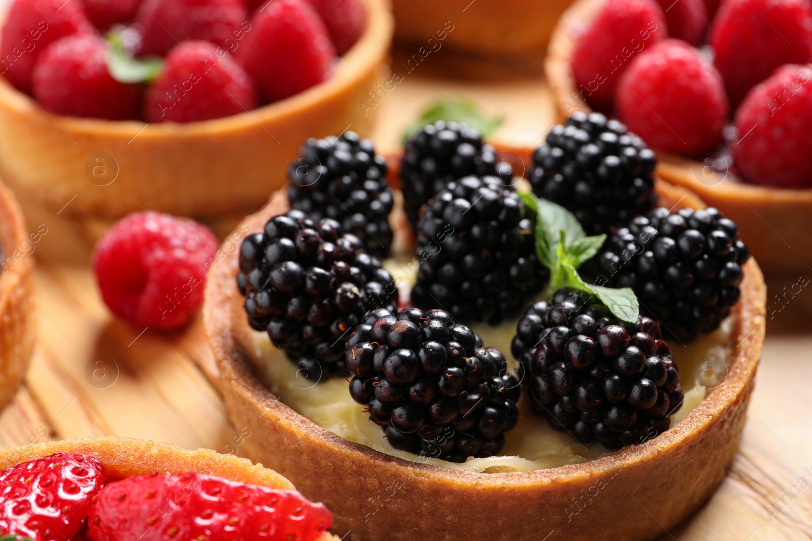 Photo of Tartlet with fresh blackberries on table, closeup. Delicious dessert
