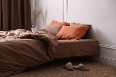 Photo of Bed with orange and brown linens in stylish room