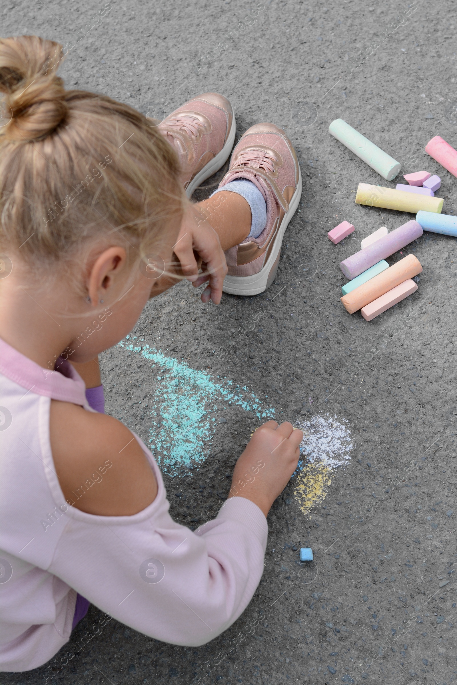 Photo of Little child drawing flower with chalk on asphalt, closeup