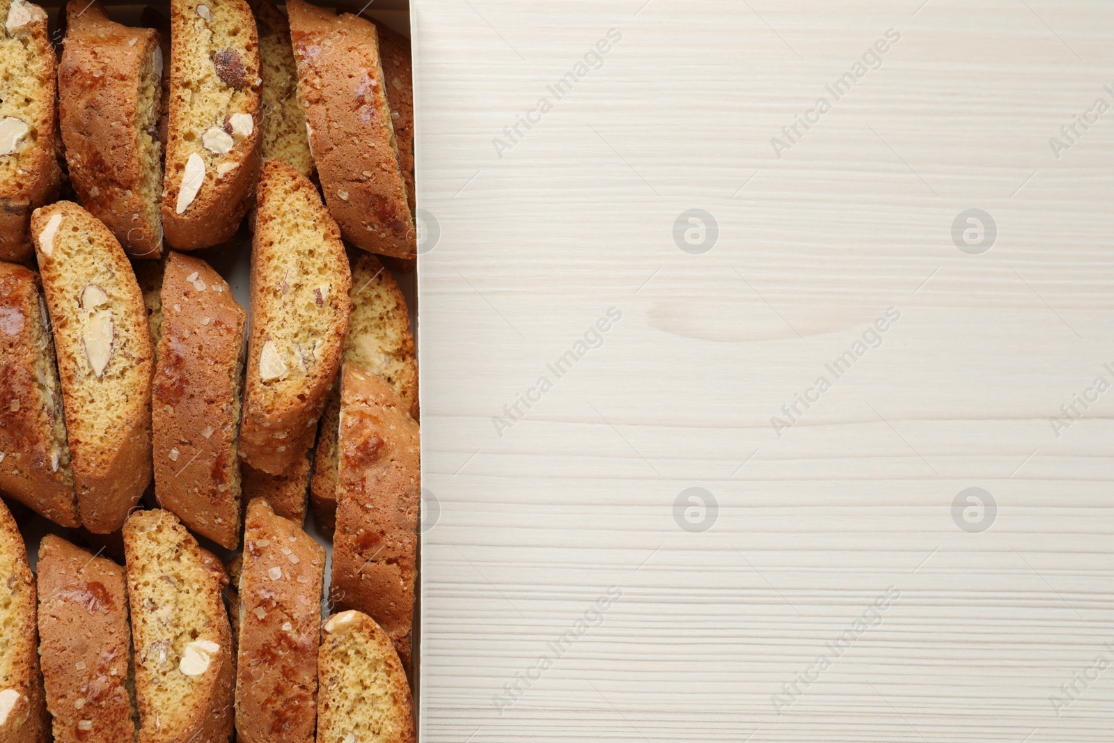 Photo of Traditional Italian almond biscuits (Cantucci) on white wooden table, top view. Space for text