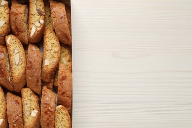 Photo of Traditional Italian almond biscuits (Cantucci) on white wooden table, top view. Space for text