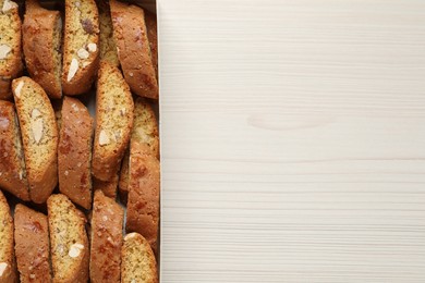 Traditional Italian almond biscuits (Cantucci) on white wooden table, top view. Space for text