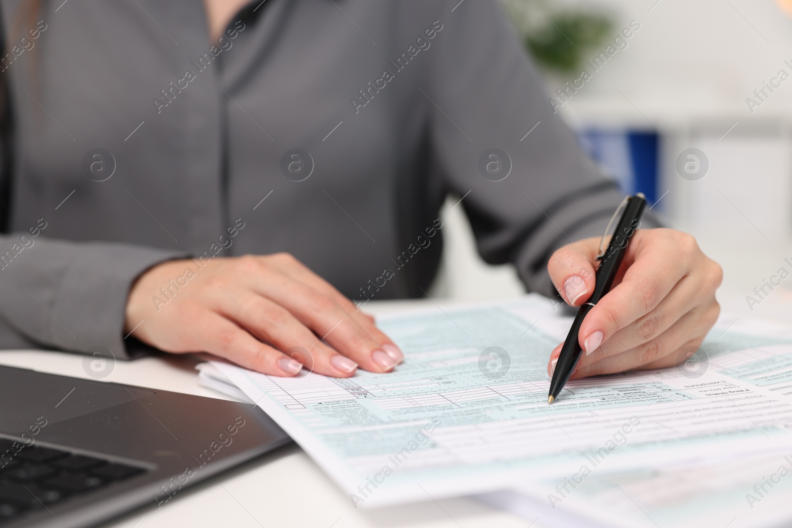 Photo of Secretary doing paperwork at table in office, closeup