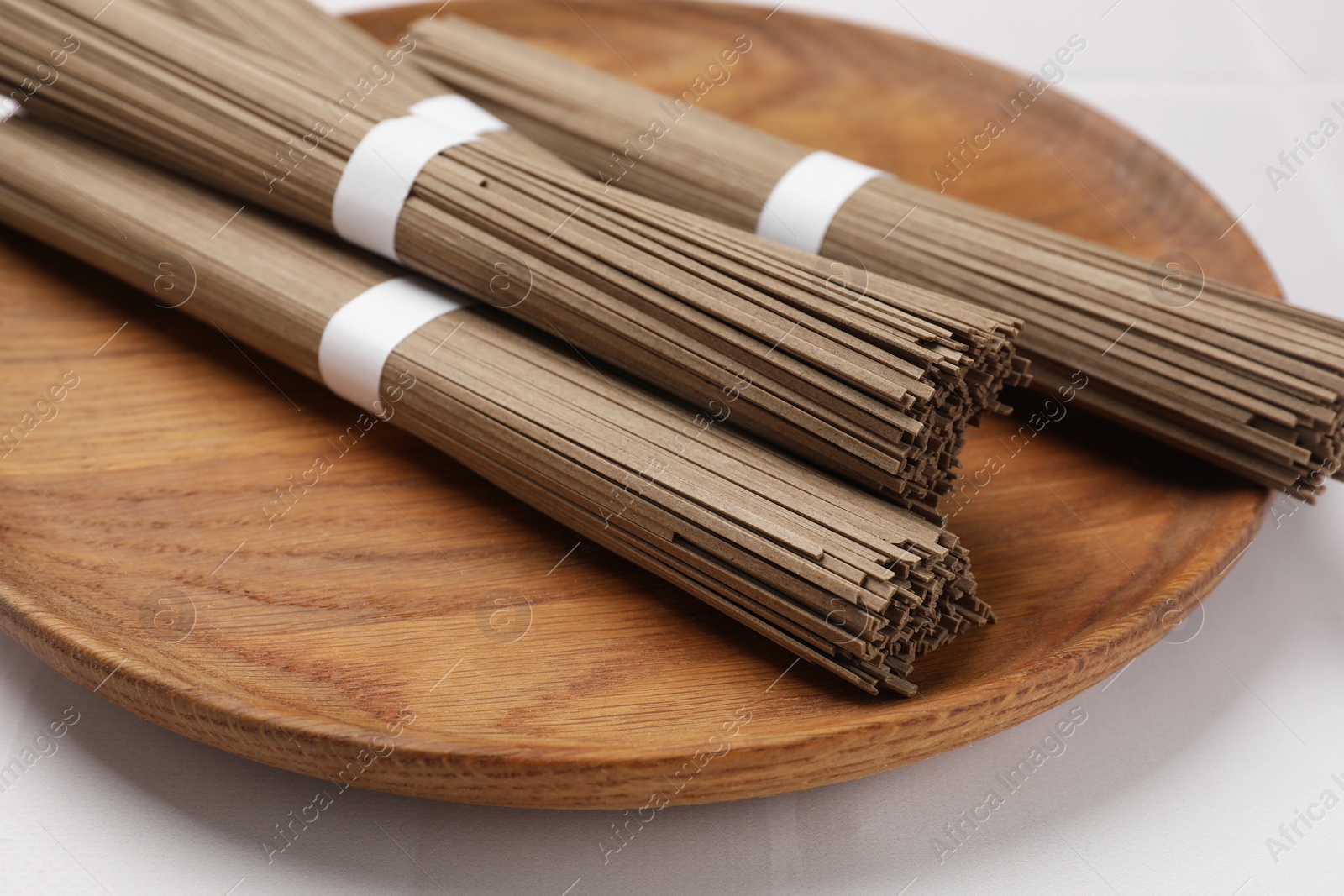 Photo of Uncooked buckwheat noodles (soba) on white table, closeup