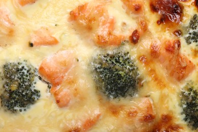 Photo of Delicious homemade quiche with salmon and broccoli as background, top view