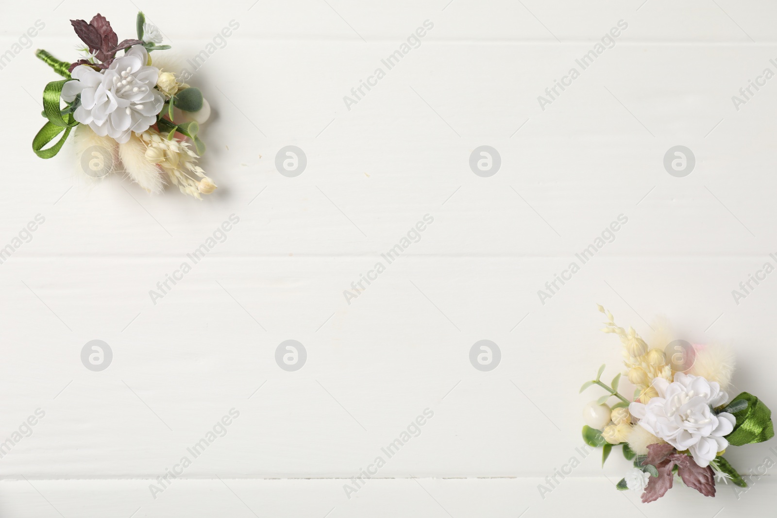 Photo of Beautiful boutonnieres on white background, flat lay. Space for text