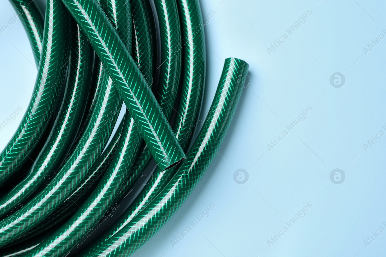 Photo of Watering hose on light blue background, top view. Space for text