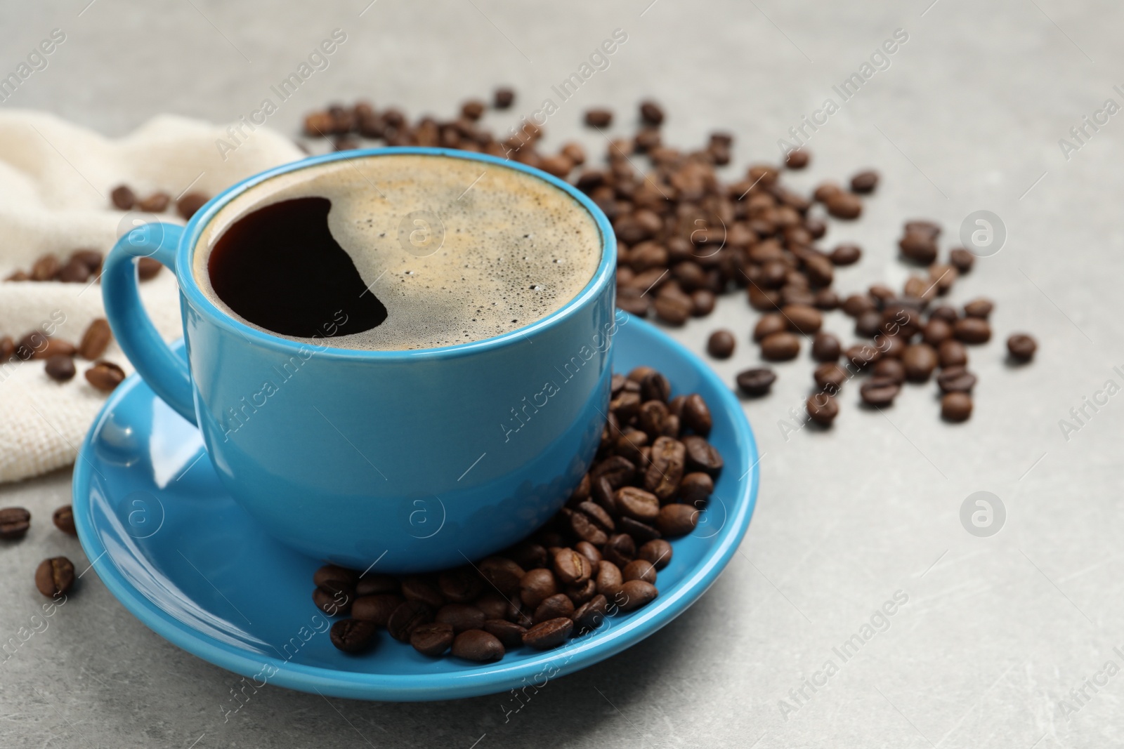 Photo of Cup of aromatic coffee and beans on light grey table
