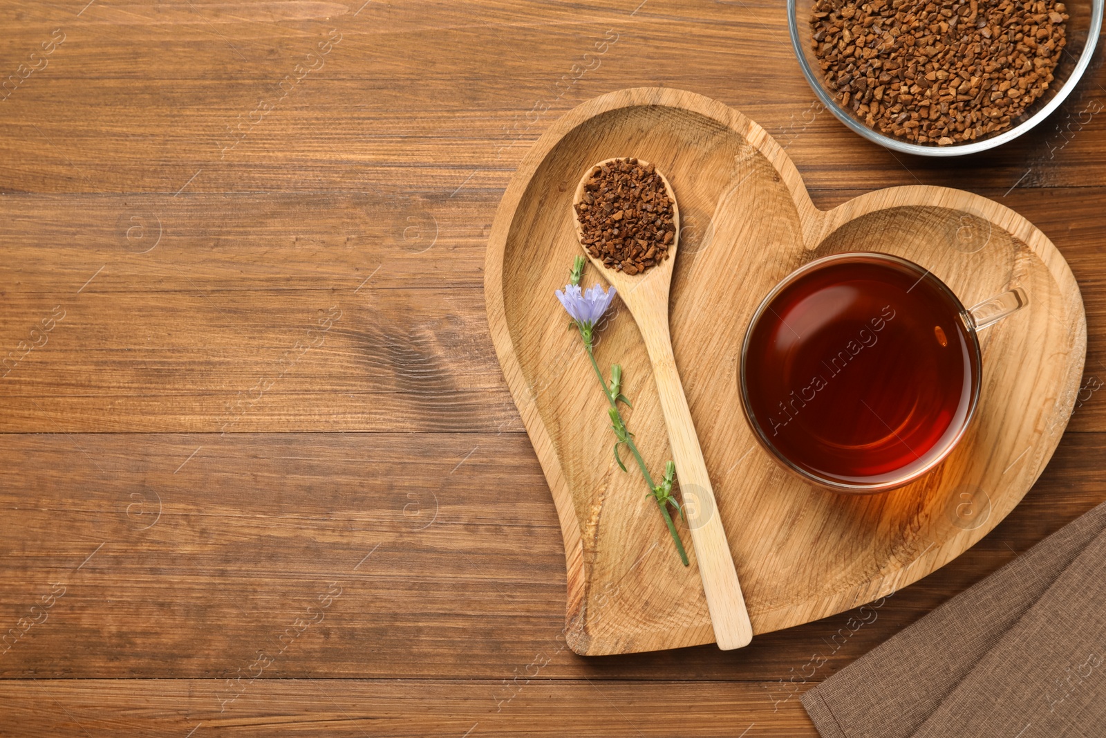 Photo of Cup of delicious chicory drink, granules and flower on wooden table, flat lay. Space for text