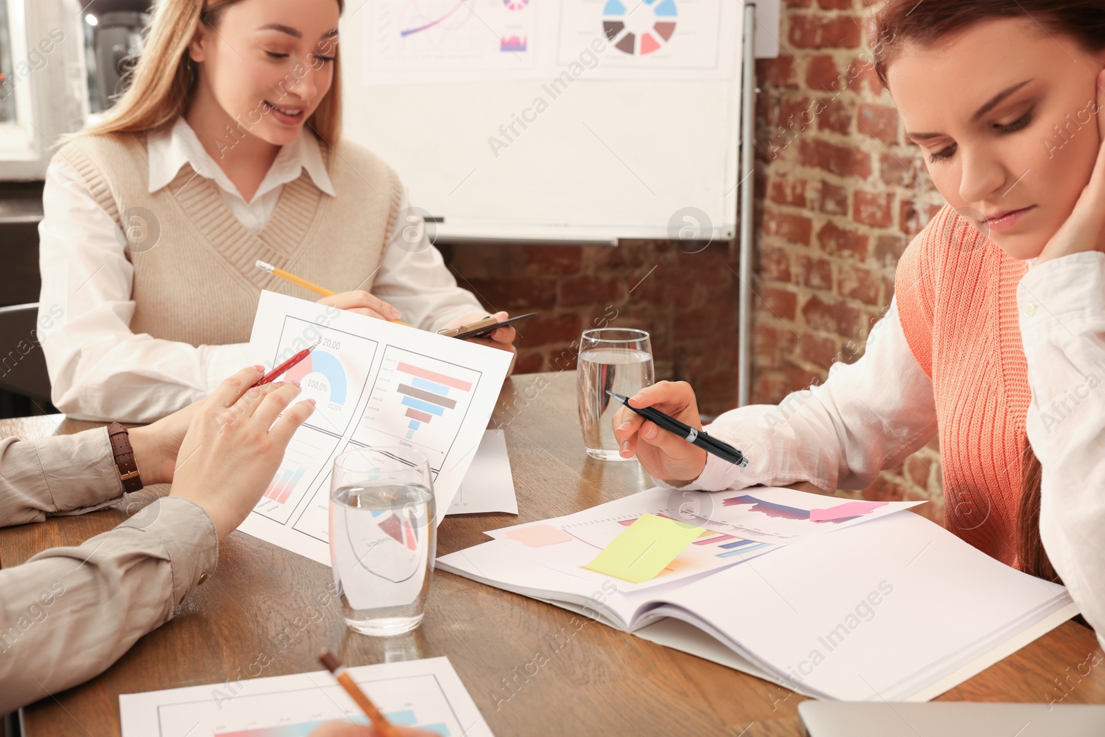 Photo of Team of employees working together at wooden table, closeup