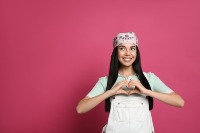 Young woman wearing stylish bandana on pink background, space for text