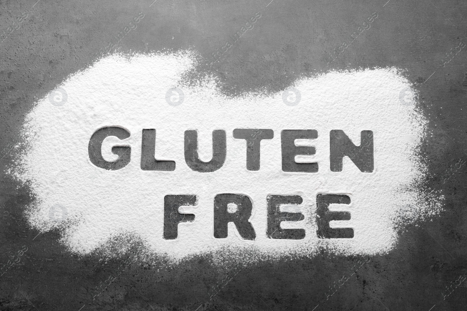 Photo of Words Gluten free written with flour on grey background, top view