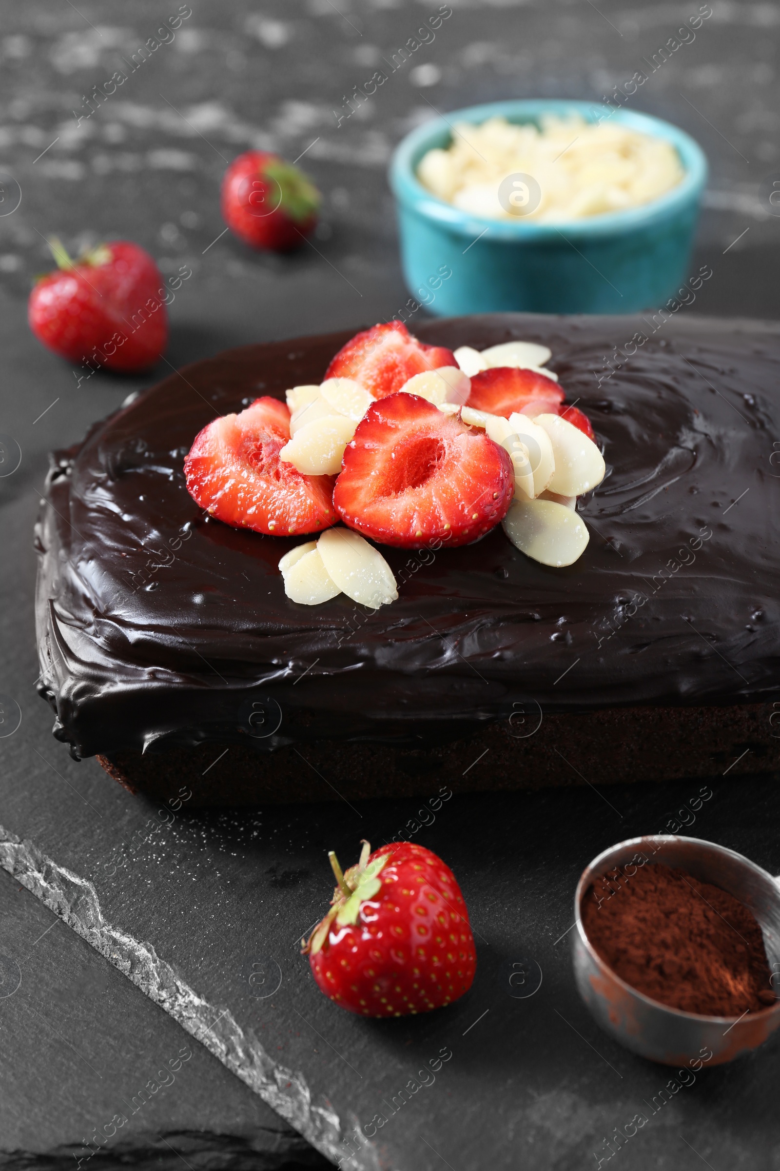 Photo of Delicious chocolate sponge cake with strawberry and almond flakes on slate board