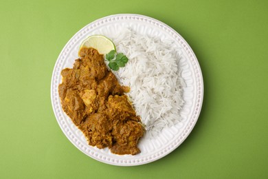 Photo of Delicious chicken curry with rice on green background, top view