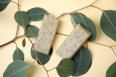 Photo of Soap bars and green leaves on beige background, flat lay. Eco friendly personal care product