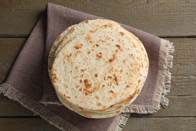 Photo of Many tasty homemade tortillas on wooden table, top view