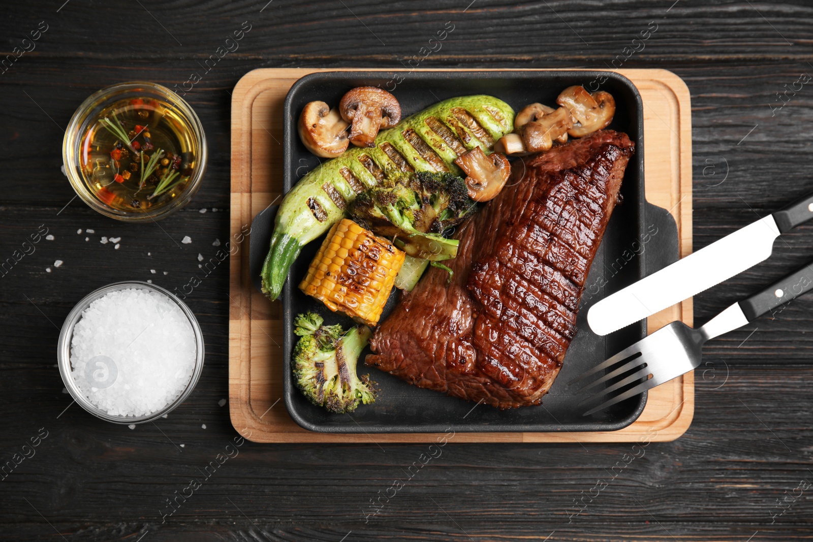 Photo of Delicious beef tenderloin served on black wooden table, flat lay