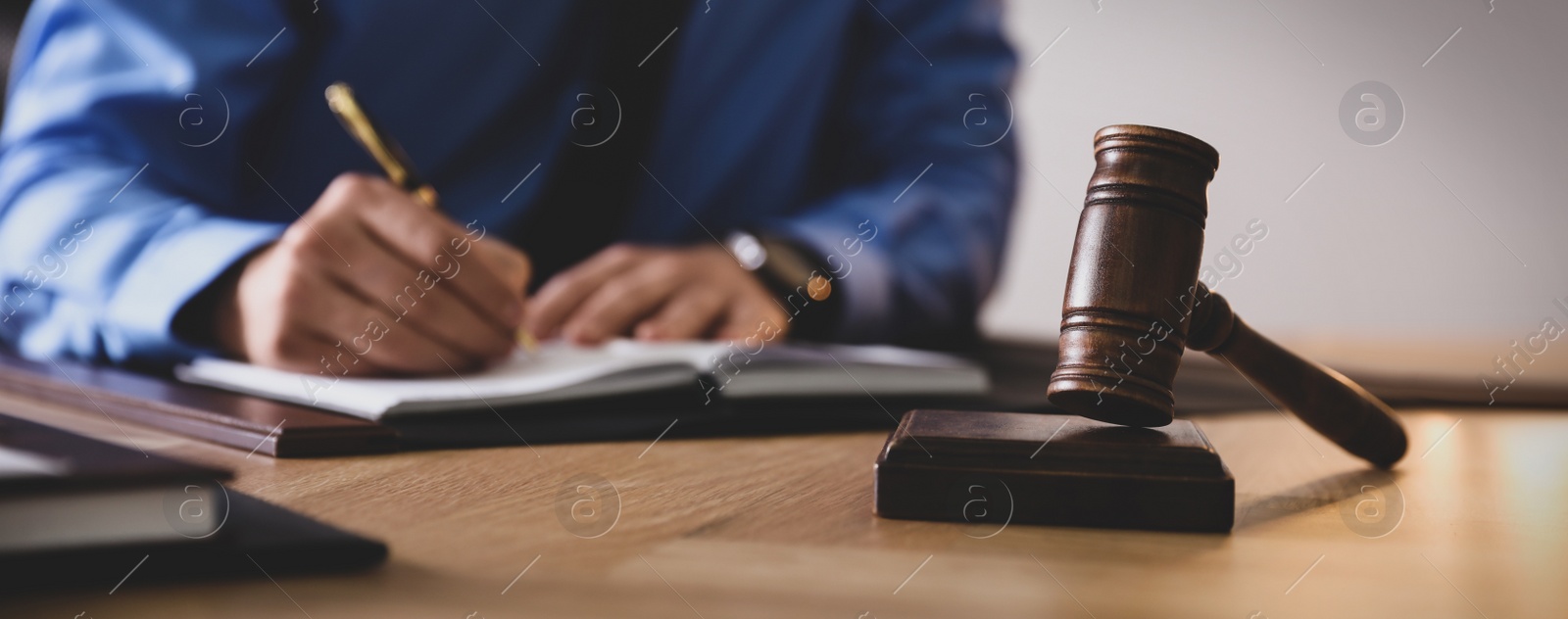 Image of Male lawyer working at table in office, focus on gavel. Banner design