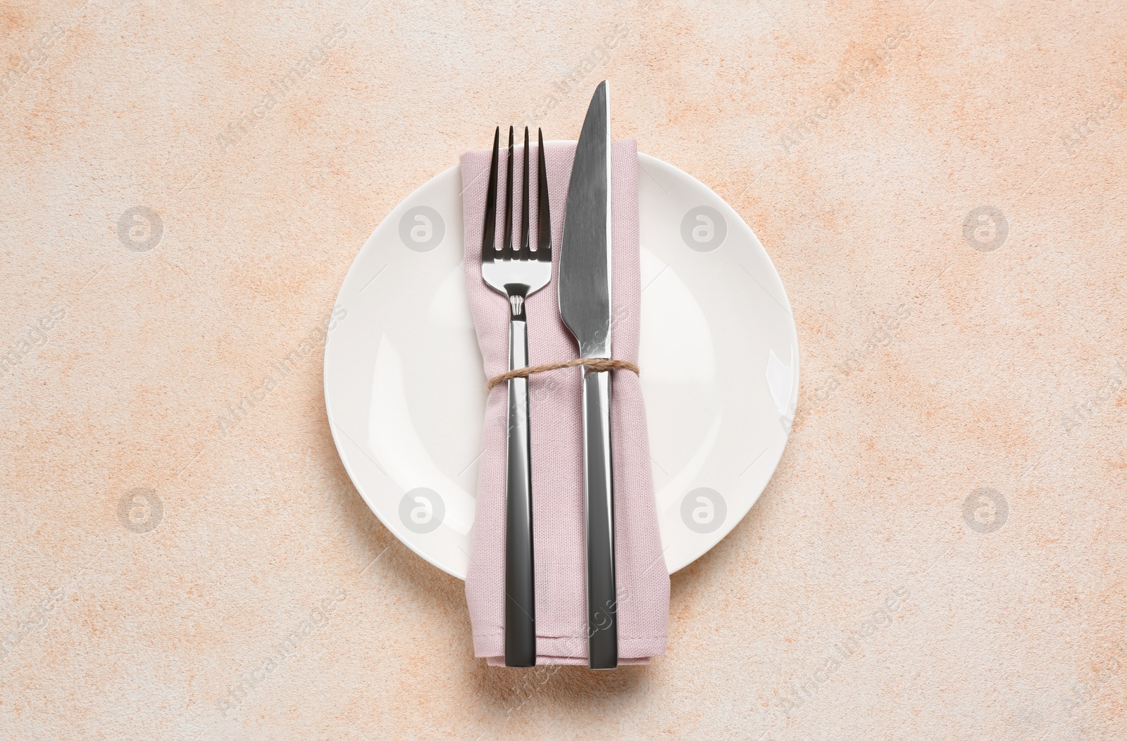 Photo of Plate, fork and knife on beige table, top view