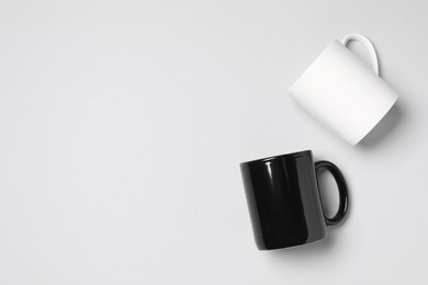 Photo of Black and white ceramic mugs on light background, flat lay. Space for text