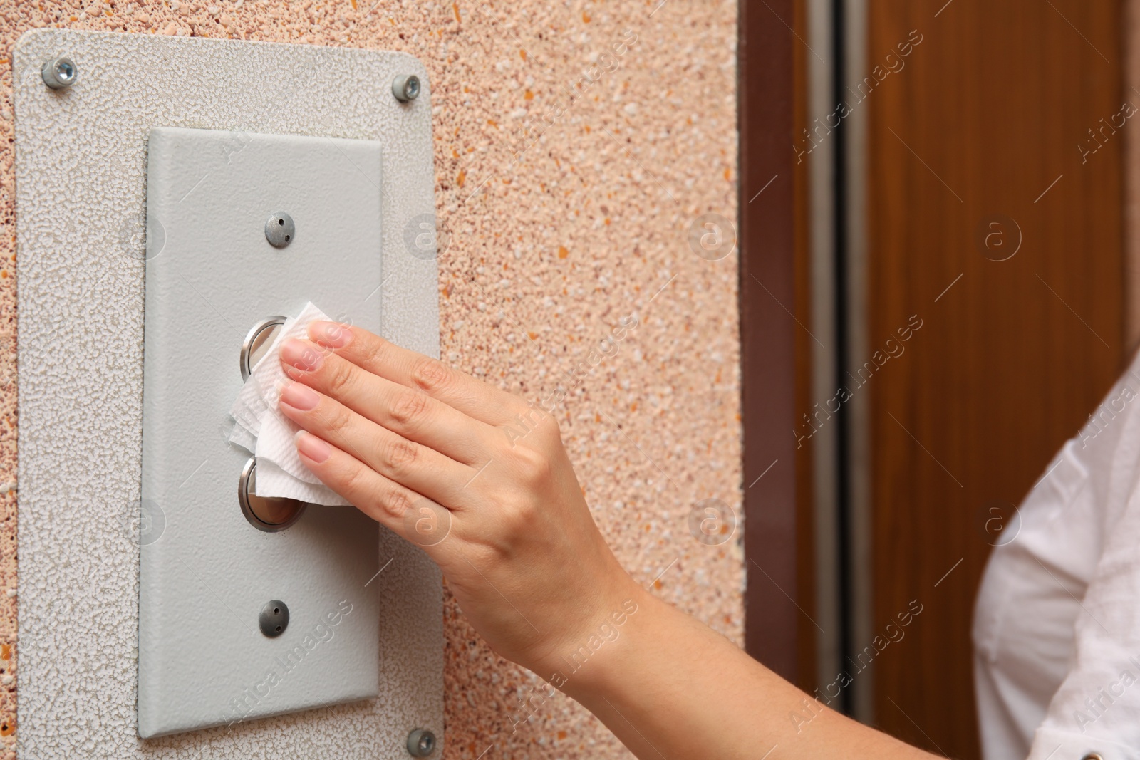 Photo of Woman using tissue paper to press elevator call button, closeup