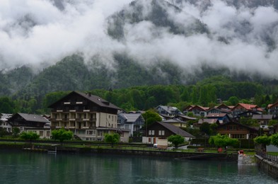 Picturesque view of beautiful village on lake shore near mountains