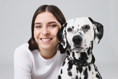 Photo of Beautiful woman with her adorable Dalmatian dog on light grey background. Lovely pet