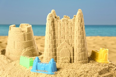 Image of Sand castles with toys on ocean beach, closeup. Outdoor play