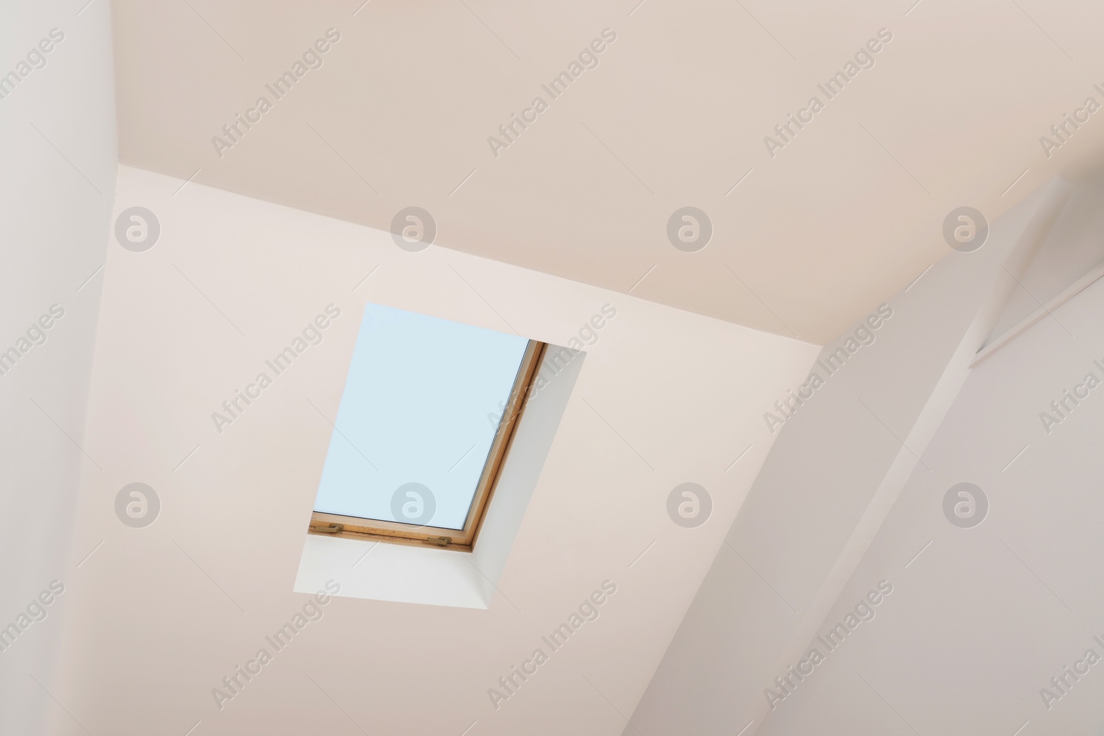 Photo of Skylight roof window and lamps on slanted ceiling in attic room, low angle view