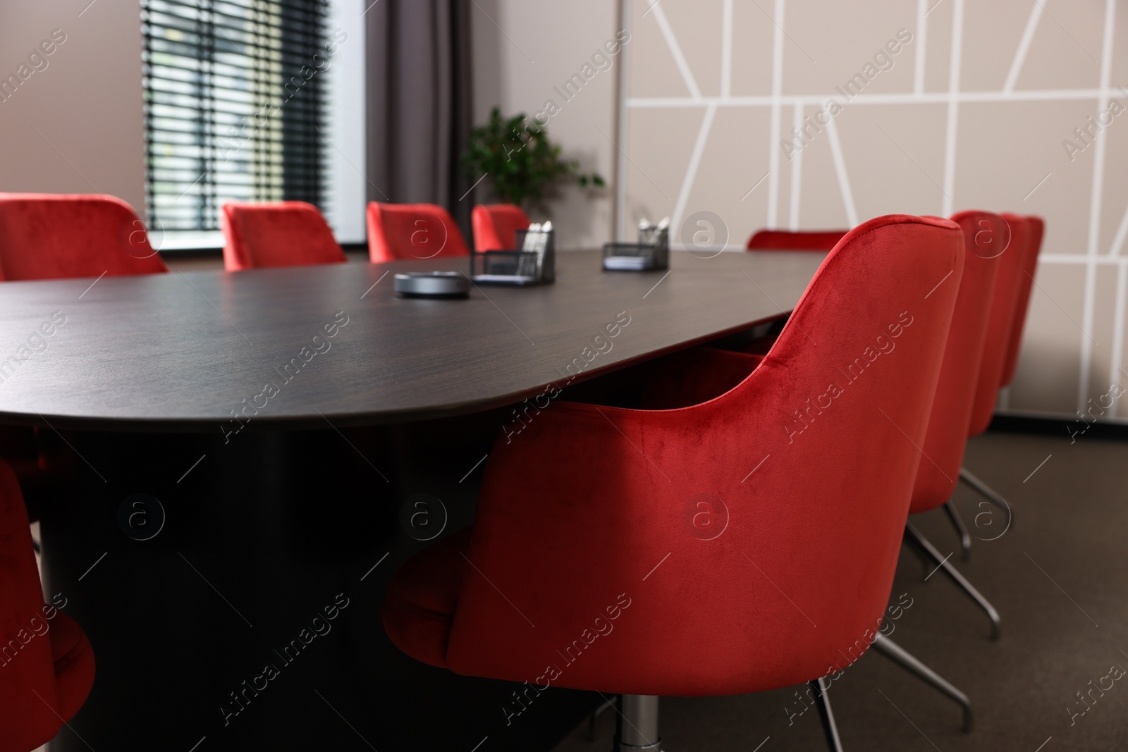 Photo of Stylish red office chairs and large wooden table in empty conference room