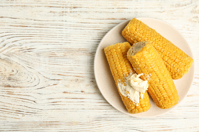 Photo of Delicious boiled corn with butter on white wooden table, top view. Space for text