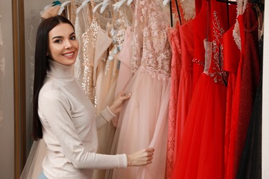Photo of Woman choosing dress in rental clothing salon