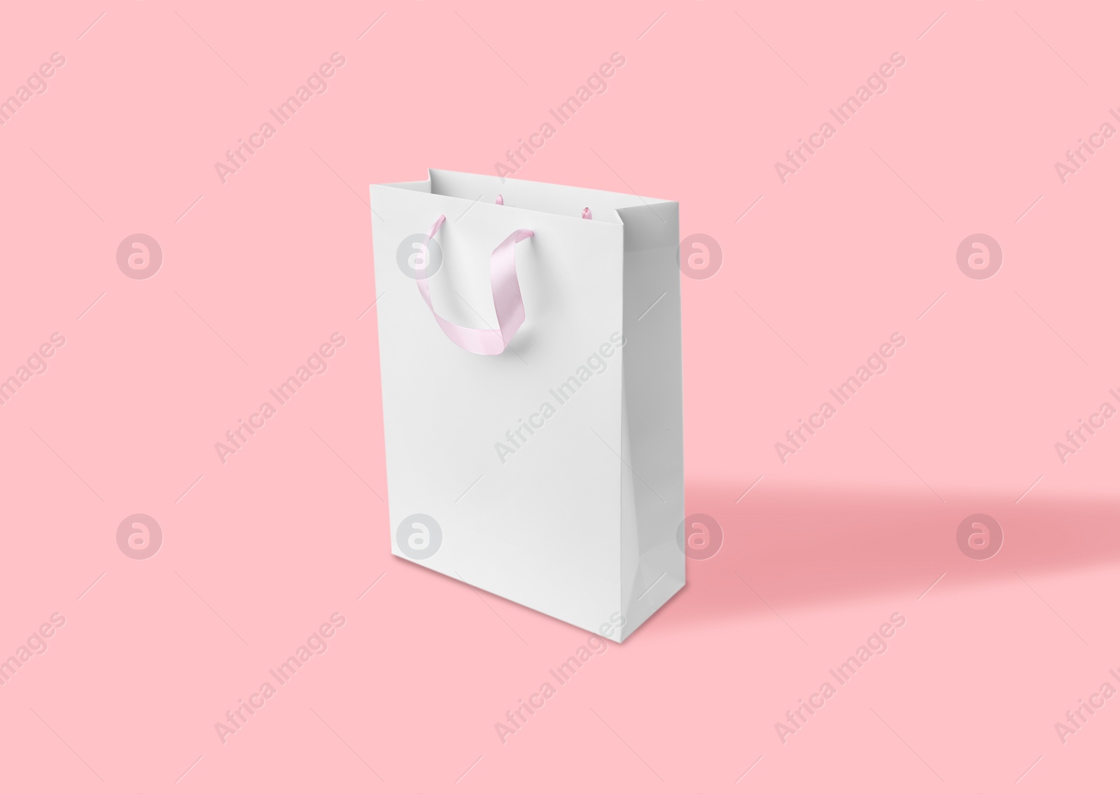 Image of White paper bag on pink background. Mockup for design