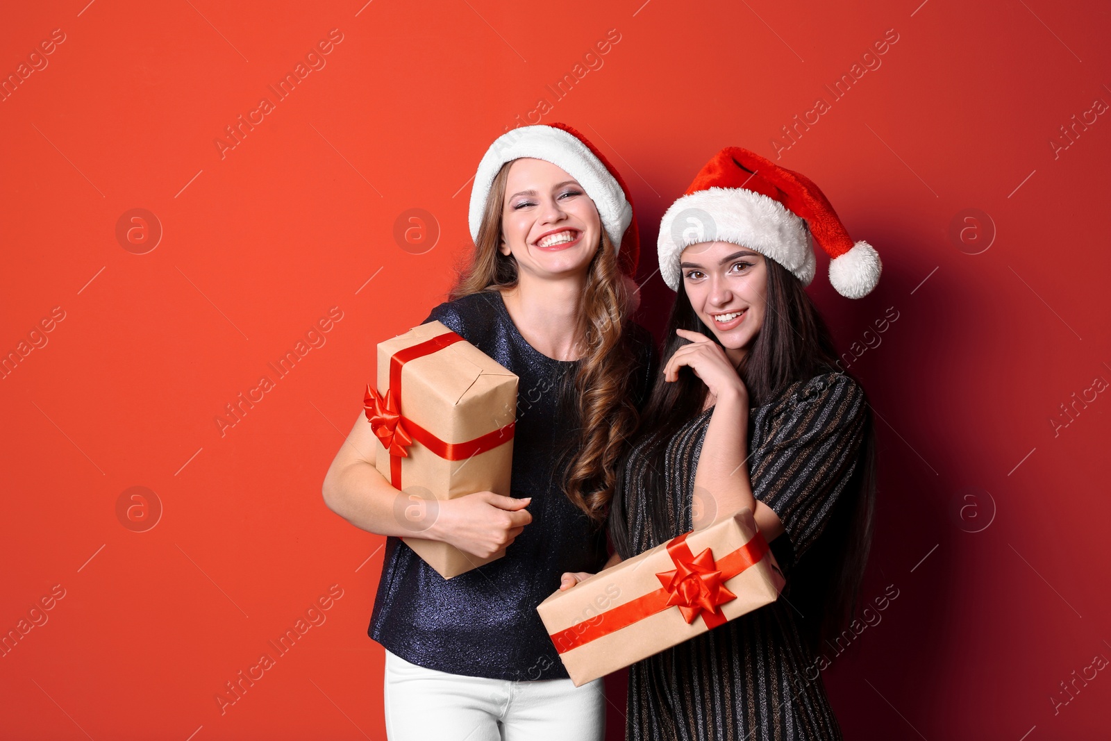 Photo of Beautiful young women in Santa hats with gift boxes on color background. Christmas celebration