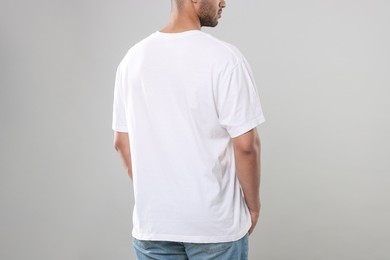 Photo of Man wearing white t-shirt on gray background, closeup