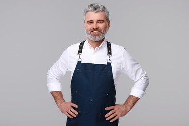 Photo of Happy man wearing kitchen apron on grey background. Mockup for design