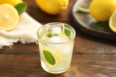 Photo of Cool freshly made lemonade in glass on wooden table, closeup