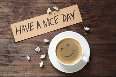 Image of Delicious coffee, flowers and card with HAVE A NICE DAY wish on wooden table, flat lay. Good morning