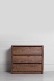 Photo of Wooden chest of drawers near white wall indoors, space for text